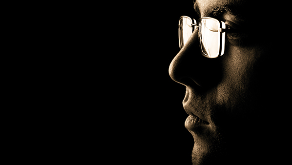 seitliches Studioportrait eines jungen Mannes mit Brille